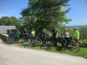 Photo of people standing with their bikes in front of a tree